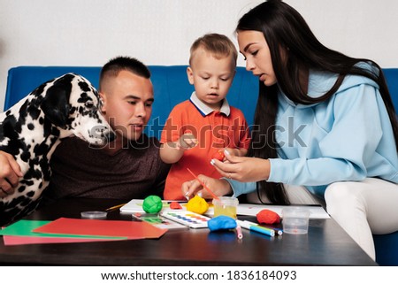 young Caucasian family with a dog do creative work at home, paint and sculpt with plasticine