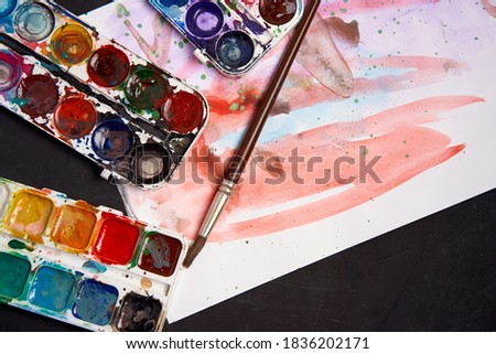 Set of watercolor paints on a black background. Brushes drawing. Creative background. School for teaching drawing. With copy space for text