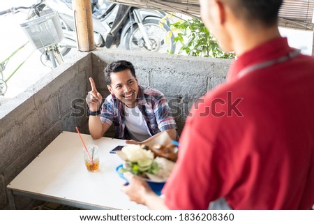 the buyer calls the stall waiter who prepares and serves side dishes at the food stall Royalty-Free Stock Photo #1836208360
