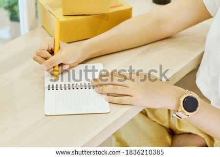 Close up of women hand writing notebook  with box in background             