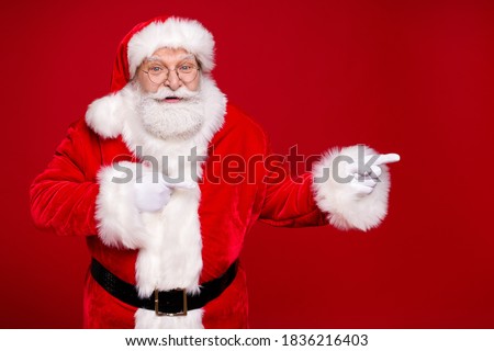 Photo of retired grandpa grey beard direct finger empty space suggest curious newyear product wear santa costume leather belt gloves coat spectacles headwear isolated red color background