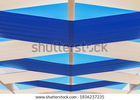 Beautiful stylish beach canopy made of intertwined white and blue ribbons. Beautiful geometric background.