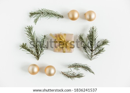 Creative flat lay with fir pine branches,craft gift box and Christmas balls on the white background. Minimalist scandinavian style.