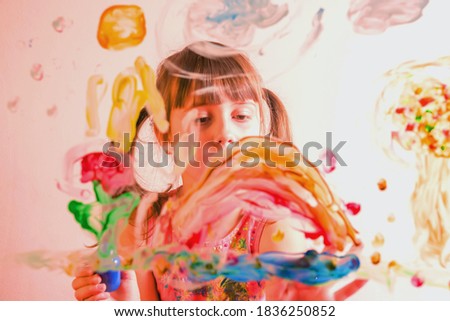 Beautiful young girl painting on glass with colorful finger. Happy childhood, art, painting lessons concept.