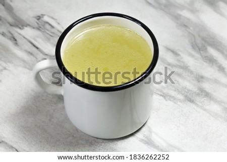 Chicken broth in a white mug on a gray marble table. Meat broth. Healthy food. Broth for the disease.