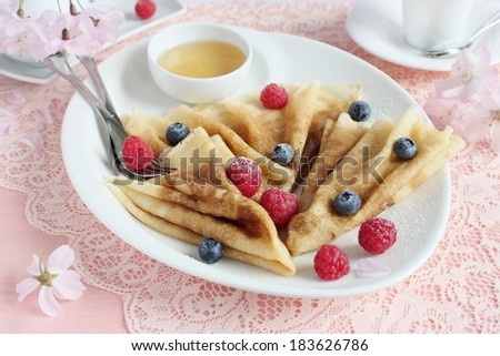 Delicious homemade pancakes with berries garnish and honey . Selective focus.