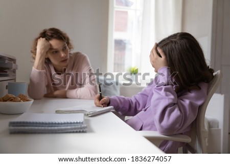 Caucasian mom help distressed unhappy teenage daughter with homework preparation, have problems with distant education. Stressed teen girl child feel unmotivated bored studying at home with mother.
