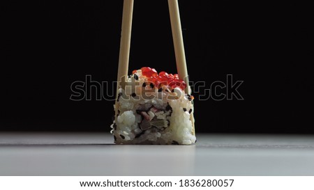 Chef cutting rolls of sushi with a knife on a stone board. - shot at a low angle. Beautiful female hands cut sushi.