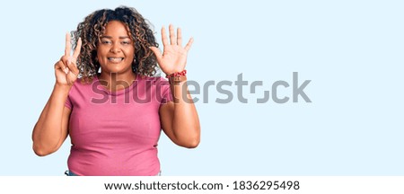 Young african american plus size woman wearing casual clothes showing and pointing up with fingers number seven while smiling confident and happy. 