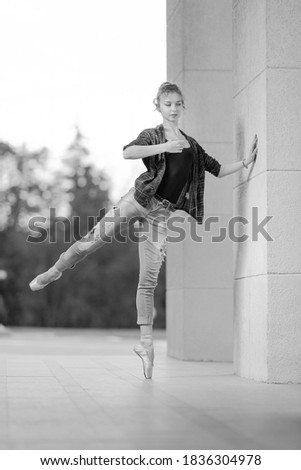 Black and white photo, ballerina girl in pointe shoes dancing and posing on the street