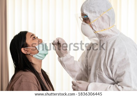 Medical staff with PPE suit test coronavirus covid-19 to asian woman by nose swab at hosputal. COVID-19 testing health care concept. Royalty-Free Stock Photo #1836306445