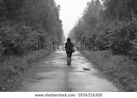 A lonely woman walks on the road in black and white