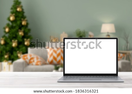 Blank display screen laptop computer on white wood table. Modern cozy comfortable home living room with Christmas decor. Home office desk workspace. Mock up copy space. Winter sales, online shopping
