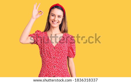 Young beautiful girl wearing dress and diadem smiling positive doing ok sign with hand and fingers. successful expression. 