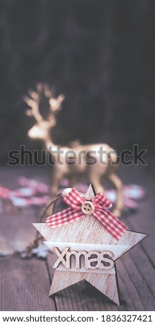 Christmas star with red bow and letters Xmas and reindeer on rustic wooden table, vertical banner background