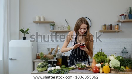 Girl making photos for social media on smartphone at kitchen. Young blogger woman preparing food, taking pictures on phone for her social accounts or video stories. Weight loss and diet
