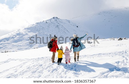 Rear view of family with two small children in winter nature, walking in the snow.