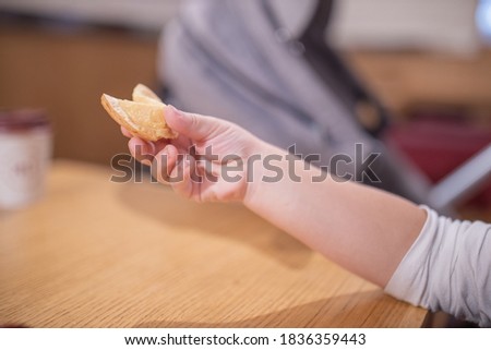 Picture of The Hand of a Little Girl Holding a Furtune Cookie with a Blurry stroller as background