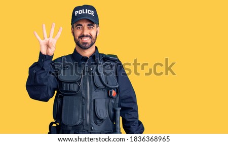 Young hispanic man wearing police uniform showing and pointing up with fingers number four while smiling confident and happy. 