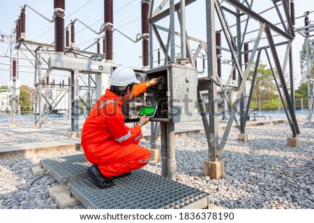 Electrical engineers inspect the electrical systems at the equipment control cabinet using data from the tablet Royalty-Free Stock Photo #1836378190