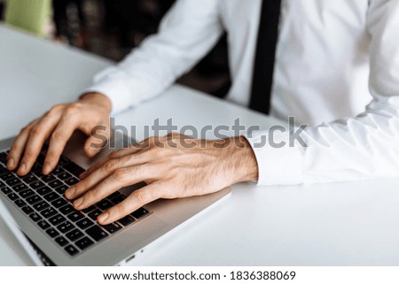 Close up photo of male hands typing on keyboard at indoor workplace