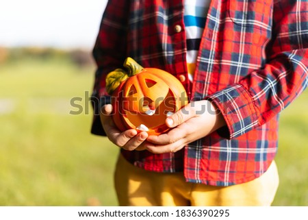 Kid's hand holding Jack'O pumpkin lamp, trick or treat on Halloween day. Concept for autumn holidays background.