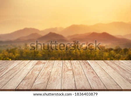 Beautiful blurry mountain range with golden light from sunset background montage photo with wooden table top for product display