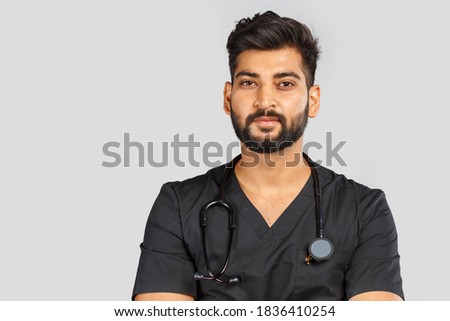 cute smiling indian doctor or surgeon in black uniform with stethoscope on gray background