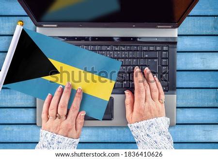 woman hands and flag of Bahamas on computer, laptop keyboard 