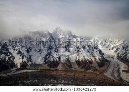 glacier and glacial lake with snow mountain under dark clouds
