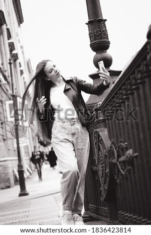 Young woman taking selfie on the busy street of a big city.