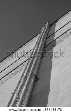 The outer wall of the building with insulated pipes. High brick wall with long pipes. Industry and architecture. Selective focus.