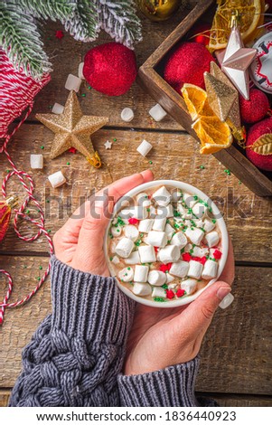 Hot chocolate with marshmallows, warm chocolate drink for Christmas morning breakfast, on wooden background with Christmas decorations, cozy winter pic. Hot chocolate cup in girls hands 