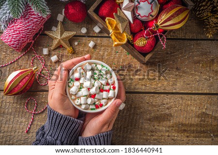 Hot chocolate with marshmallows, warm chocolate drink for Christmas morning breakfast, on wooden background with Christmas decorations, cozy winter pic. Hot chocolate cup in girls hands 
