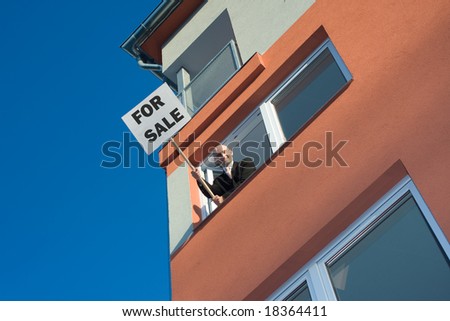 Proactive estate agent holding for sale sign out of window on high floor of apartment block.