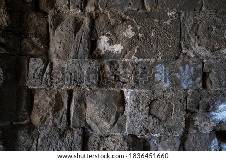 Old stone wall made of natural material, rough texture dark texture, castle and church wall close up.