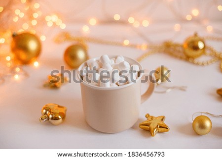 A mug of coffee and marshmallows , with Golden Christmas balls on a background of glowing lights. New year's sale concept