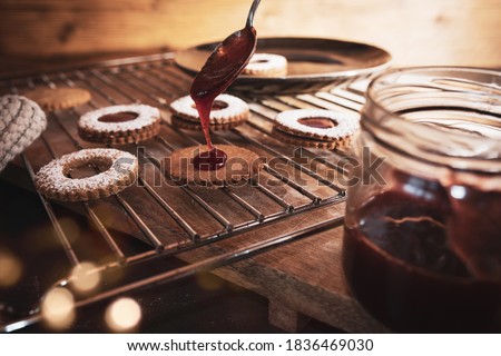Baking traditional linzer cookies with strawberry jam. Christmas background with golden bokeh and short depth of field for baking concepts with space for text.