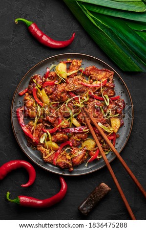 Kkanpunggi or Korean Spicy Garlic Fried Chicken on black plate on dark slate table top. Kan Pung Gi is korean and chinese cuisine dish. Typical asian food and meal. Royalty-Free Stock Photo #1836475288