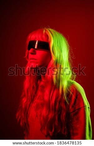 Young caucasian woman wearing smart glasses on red background - Blonde young female wearing sci-fi eye glasses isolated on background - augmented reality, wereable technology, sci-fi concept