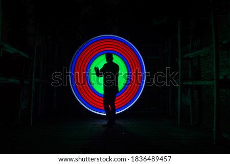 One people standing alone against a red and green circle light painting as the backdrop