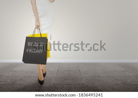 Women carrying a shopping bag with a white wall background. Black Friday concept