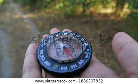 Extreme close-up of a transparent modern compas in the forest background. Concept of travel, adventure, expedition 4k
