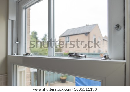 Detailed view of a newly installed, energy saving double glazed sash window looking to  small patio area. Royalty-Free Stock Photo #1836511198