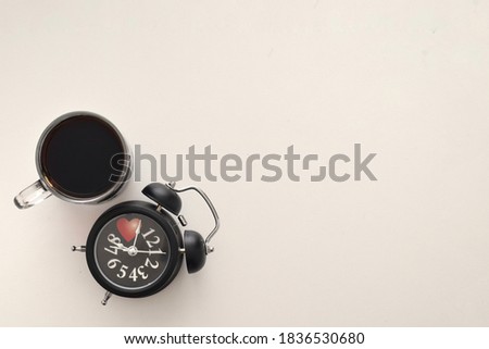 An image of alarm clock with a cup of black coffee isolated in white background. Minimalist and food concept. Image can be used as background.