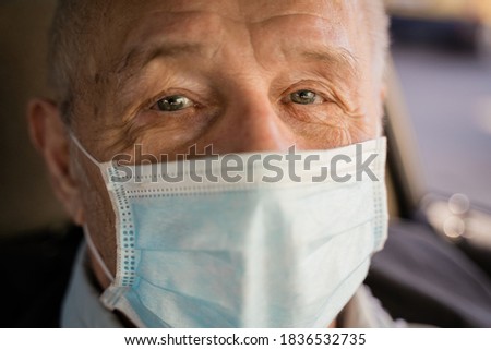 Caucasian elderly man close up portrait with face mask. Covid-19 risk group. Pandemic quarantine