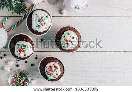 Chocolate Christmas cupcake with colored sugar topping on whithe wooden background. Top view with copy space