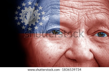 Portrait of older lady with painted national flag of Myanmar