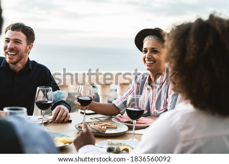 Young people doing appetizer and drinking red wine together on house patio 