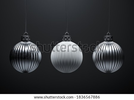 Three vertically striped Christmas balls on dark gray background. White and silver metal textured baubles. Christmas decoration, festive atmosphere concept. Black and white.